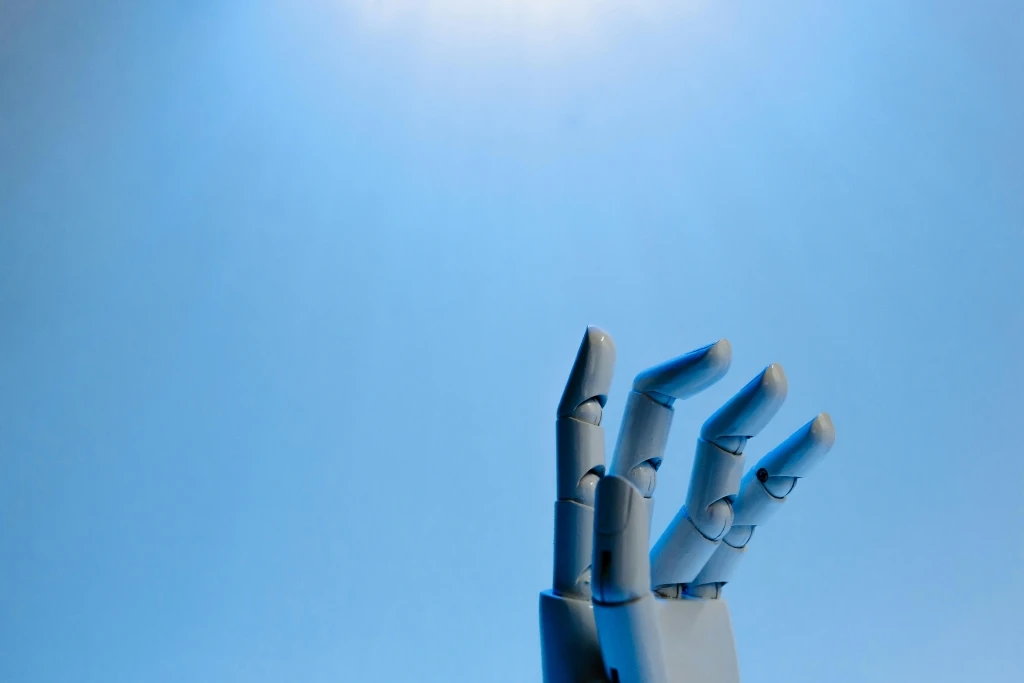 Robotic Hand waving with a blue background - photo by Tara Winstead