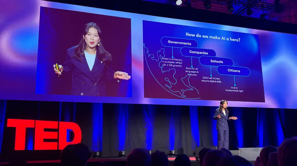 Mengchen Dong on stage at TED AI with a slide behind her